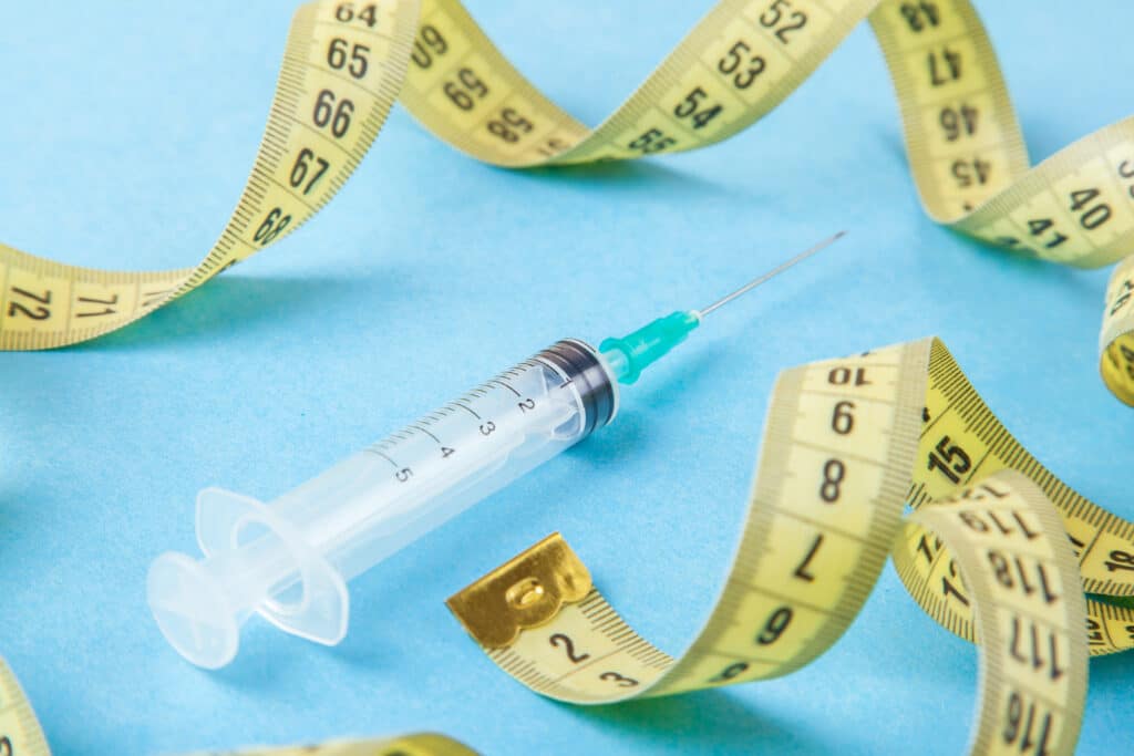 Syringe containing a skinny shot with a tape measure surrounding it