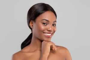 Beautiful young woman rests her face on her chin, smiling after her Aquagold treatment