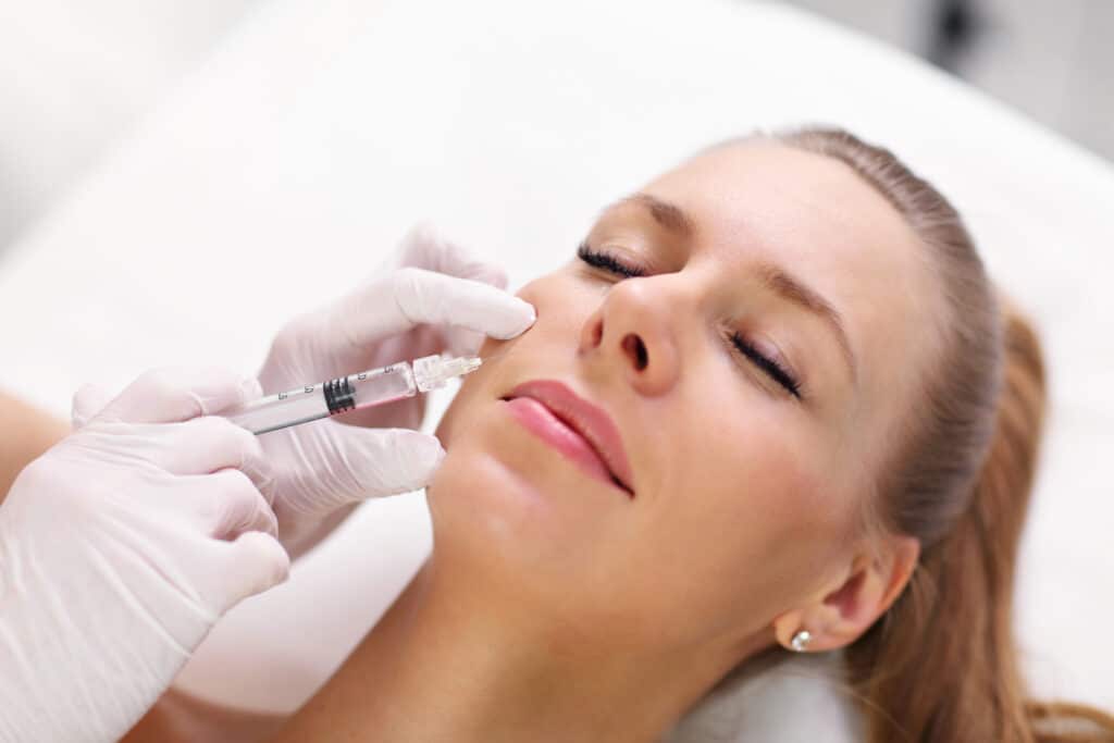 A pretty blonde woman closes her eyes during a Botox session