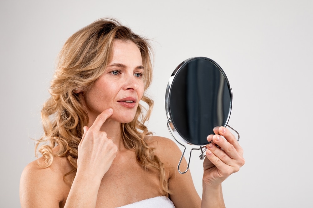 Woman in menopause looks in a mirror in Houston and considers BHRT to improve her appearance